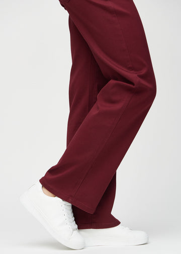 Loose jeans för kvinnor i mörkröd, färgen Santas. Närbild vid anklarna på en modell, som visar de vida bensluten.
