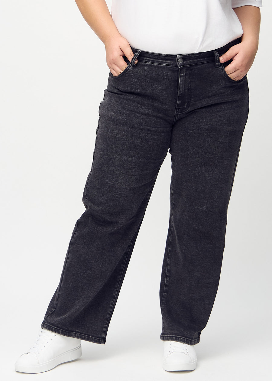 Mörkgrå denim loose jeans, modellnamn Shadows, som är löstsittande med mycket vidd i benen på en plus-size-modell, sedd framifrån.