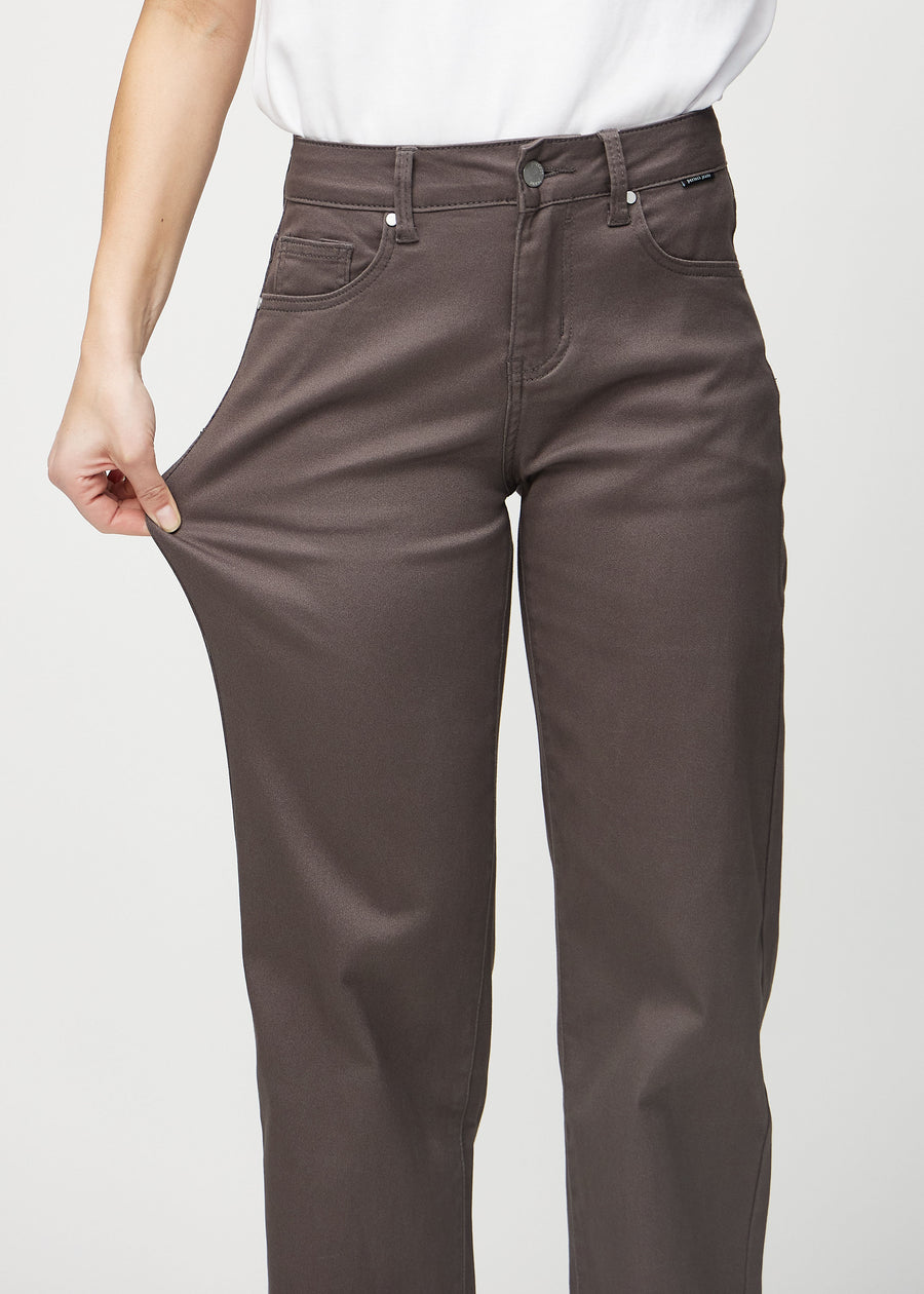 Loose jeans för kvinnor i gråbrun, färgen Thunders. En modell drar i jeanstyget vid låret för att visa stretchen.