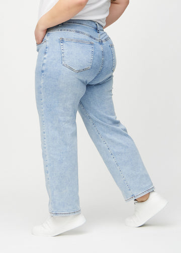 Ljus denim loose jeans sedd från sidan på en plus-size-modell.