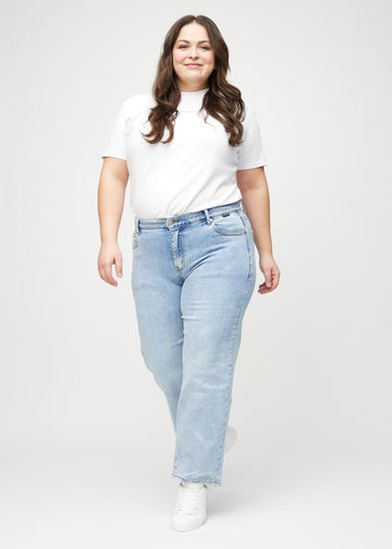 Helbild av en plus-size-modell i ljus denim loose jeans.
