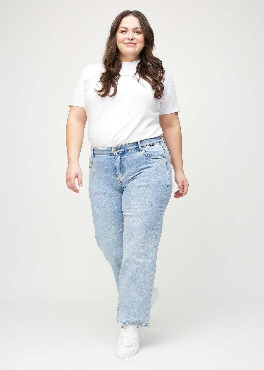 Helbild av en plus-size-modell i ljus denim loose jeans.