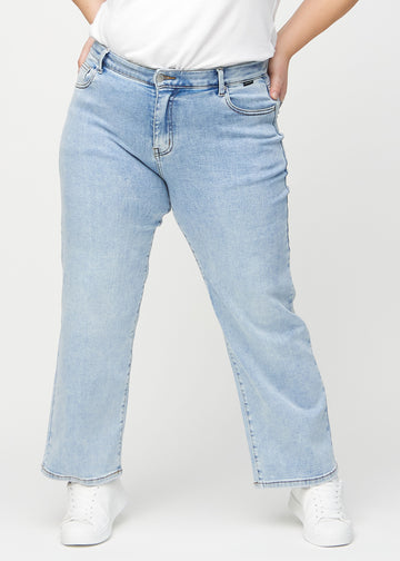 Ljus denim loose jeans, modellnamn Waves, som sitter löst med mycket vidd i benen på en plus-size-modell, sedd framifrån.