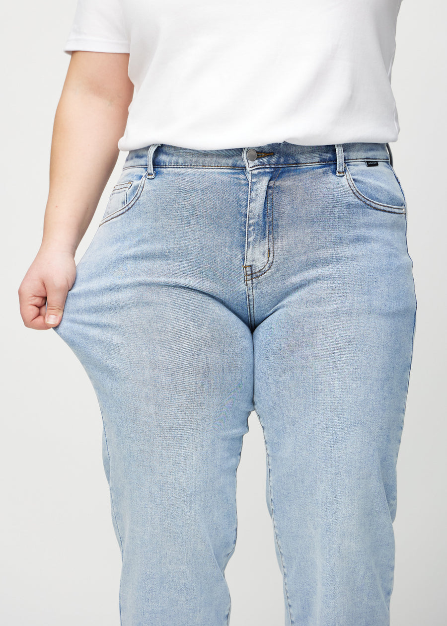 Plus-size-modellen sträcker jeansen vid låret för att visa stretch.