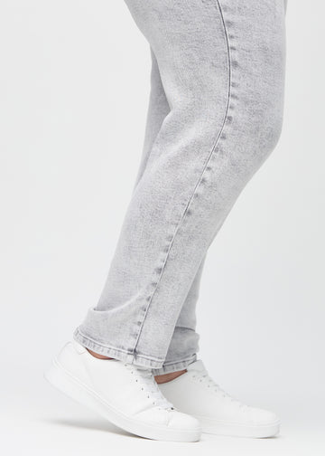Regularjeans för kvinnor i ljusgrå, färgen Ashes. Närbild vid anklarna på en plus size-modell, som visar de raka bensluten.
