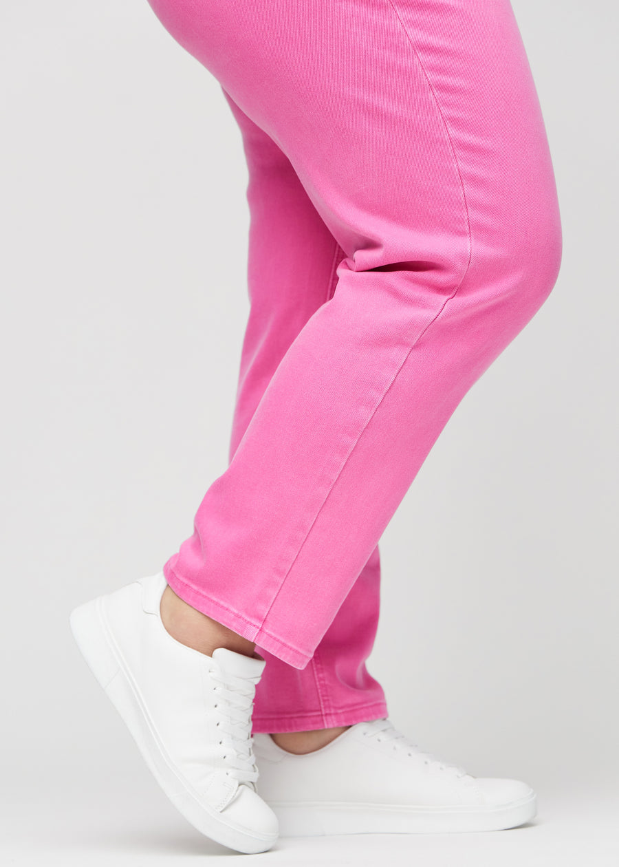 Regularjeans för kvinnor i ljusrosa, färgen Flamingos. Närbild vid anklarna på en plus size-modell, som visar de raka bensluten.