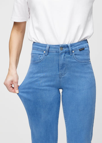 Regularjeans för kvinnor i blå, färgen Geraniums. En modell drar i tyget vid låret för att visa stretchen.