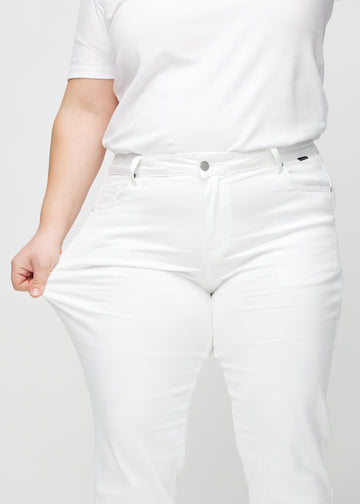Regularjeans för kvinnor i vit, färgen Marguerites. En plus size-modell drar i tyget vid låret för att visa stretchen.