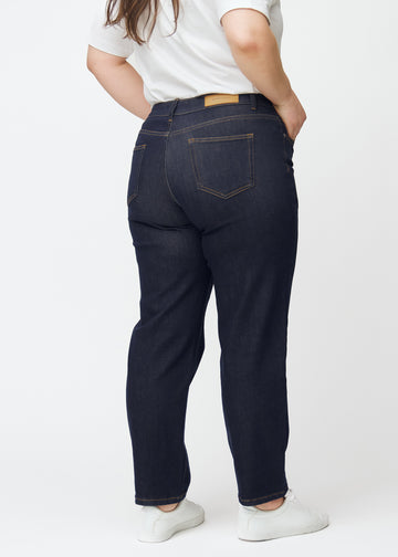 Djupt mörkblå denim jeans för kvinnor i färgen Midnights sedd bakifrån på plus size-modell.