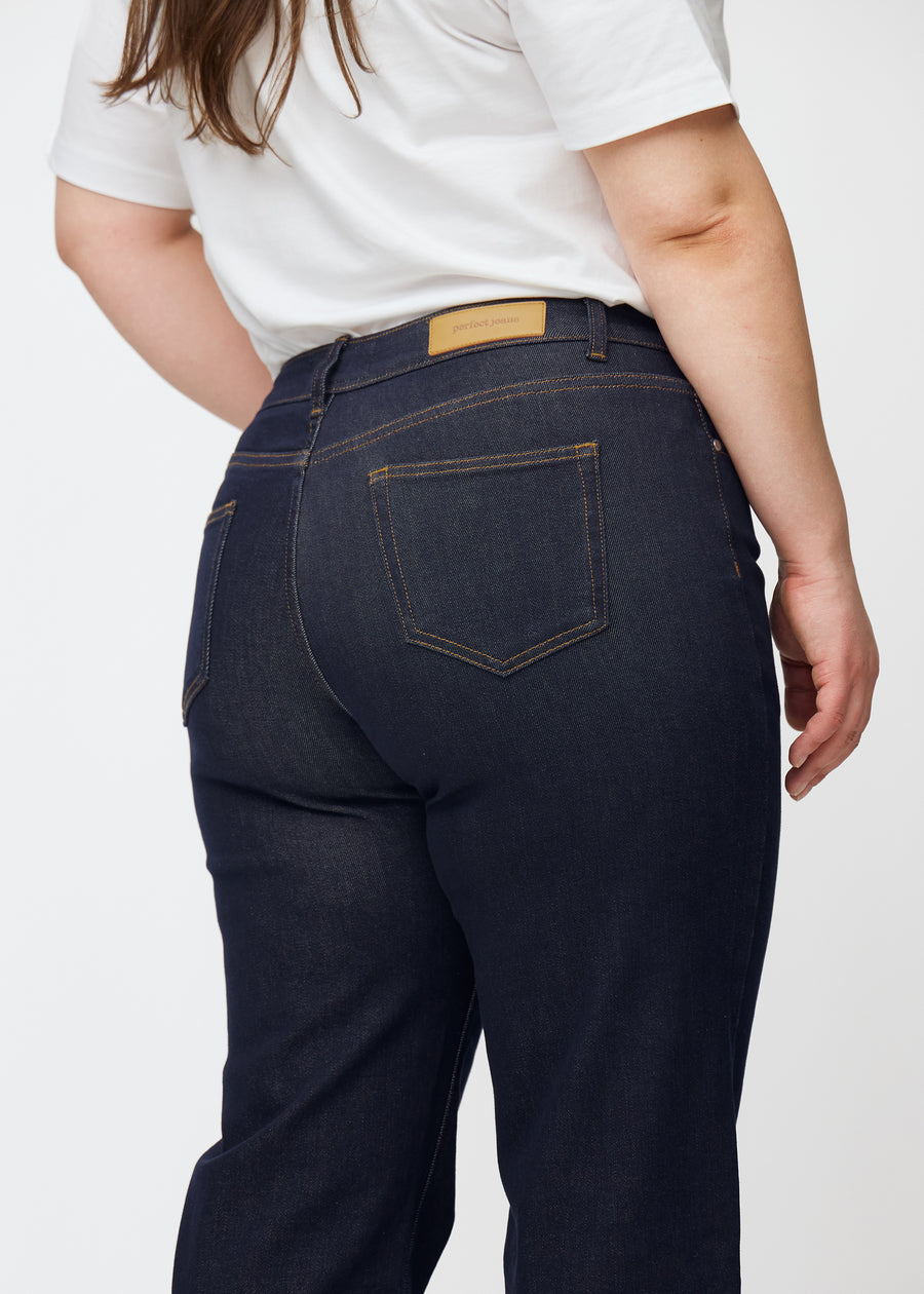 Djupt mörkblå denim jeans för kvinnor i färgen Midnights sedd bakifrån i närbild på plus size-modell.