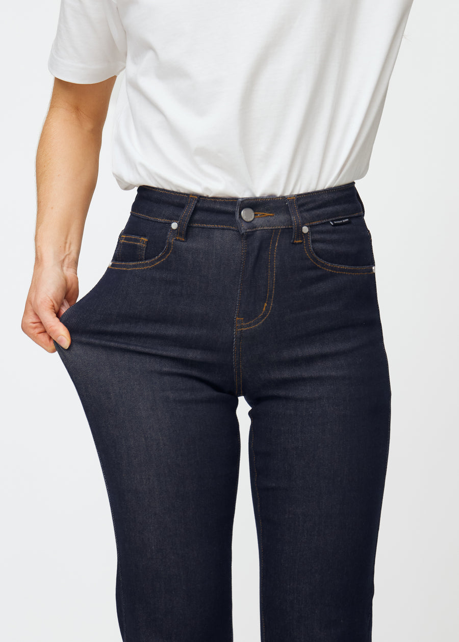 Modellen sträcker den djupt mörkblå denimen jeans för kvinnor i färgen Midnights vid låret för att visa materialets stretch.