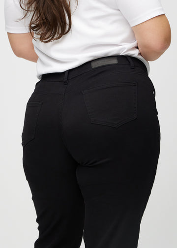 Regularjeans för kvinnor i svart, färgen Ravens. Närbild bakifrån på en plus size-modell, som visar passform och detaljer.