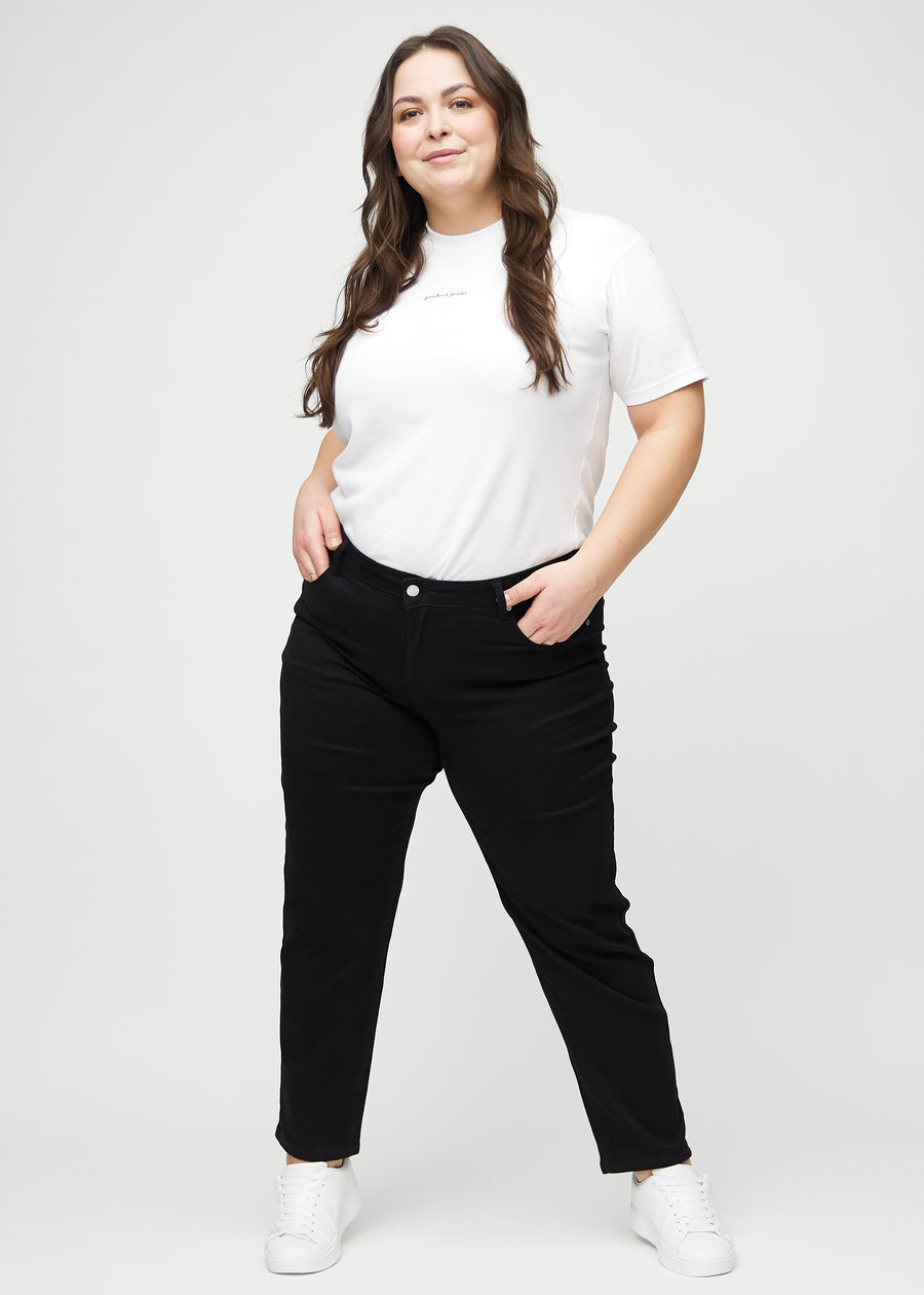 Regularjeans för kvinnor i svart, färgen Ravens. Helbild av en plus size-modell som bär jeansen.