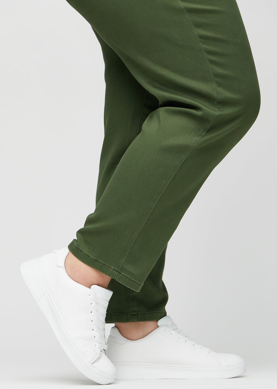 Regularjeans för kvinnor i mörkgrön, färgen Renewals. Närbild vid anklarna på en plus size-modell, som visar de raka bensluten.