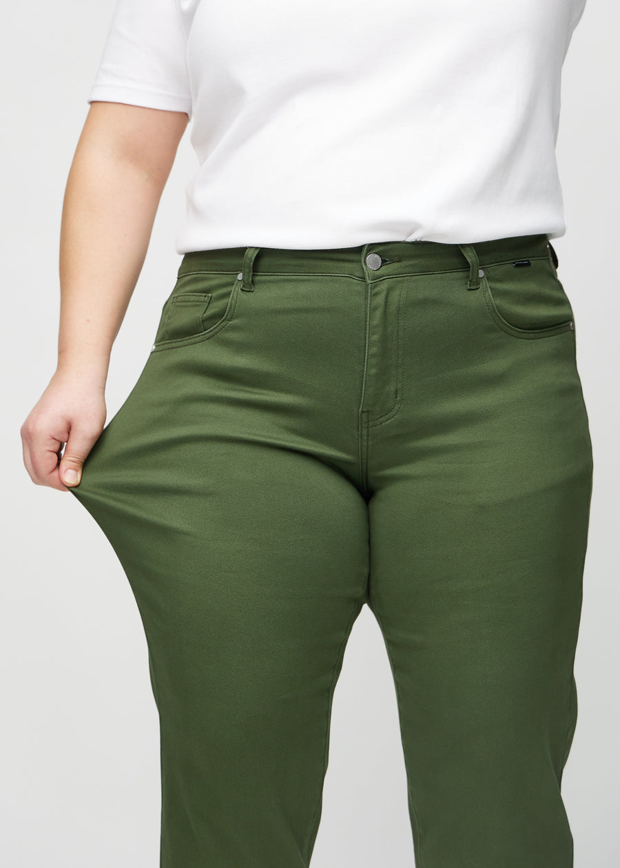 Regularjeans för kvinnor i mörkgrön, färgen Renewals. En plus size-modell drar i tyget vid låret för att visa stretchen.