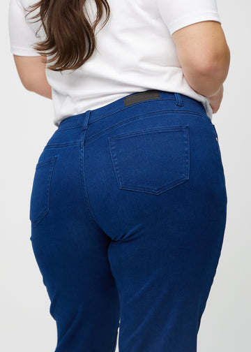 Regularjeans för kvinnor i mörkblå, färgen Royals. Närbild bakifrån på en plus size-modell, som visar passform och detaljer.