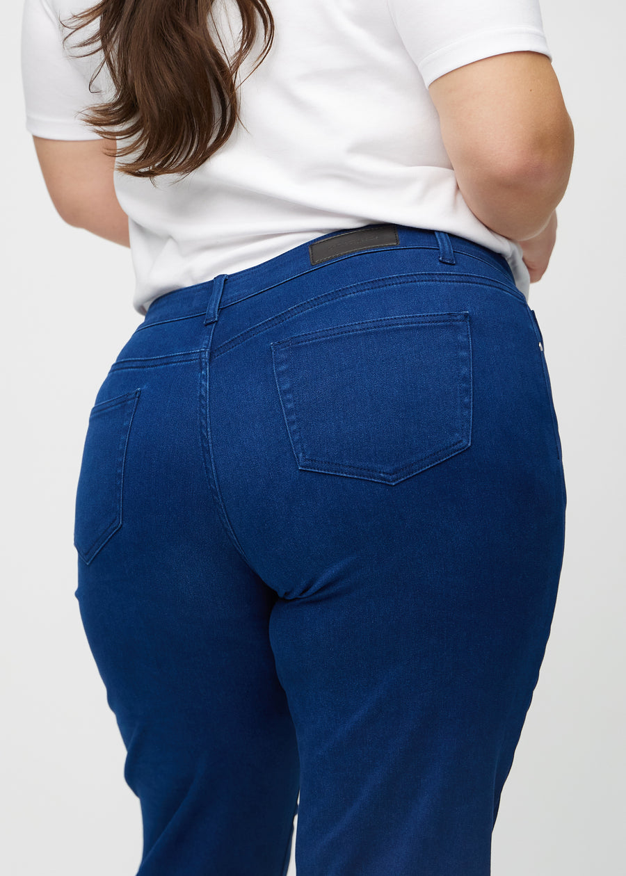 Regularjeans för kvinnor i mörkblå, färgen Royals. Närbild bakifrån på en plus size-modell, som visar passform och detaljer.