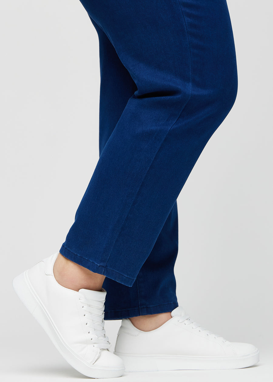 Regularjeans för kvinnor i mörkblå, färgen Royals. Närbild vid anklarna på en plus size-modell, som visar de raka bensluten.
