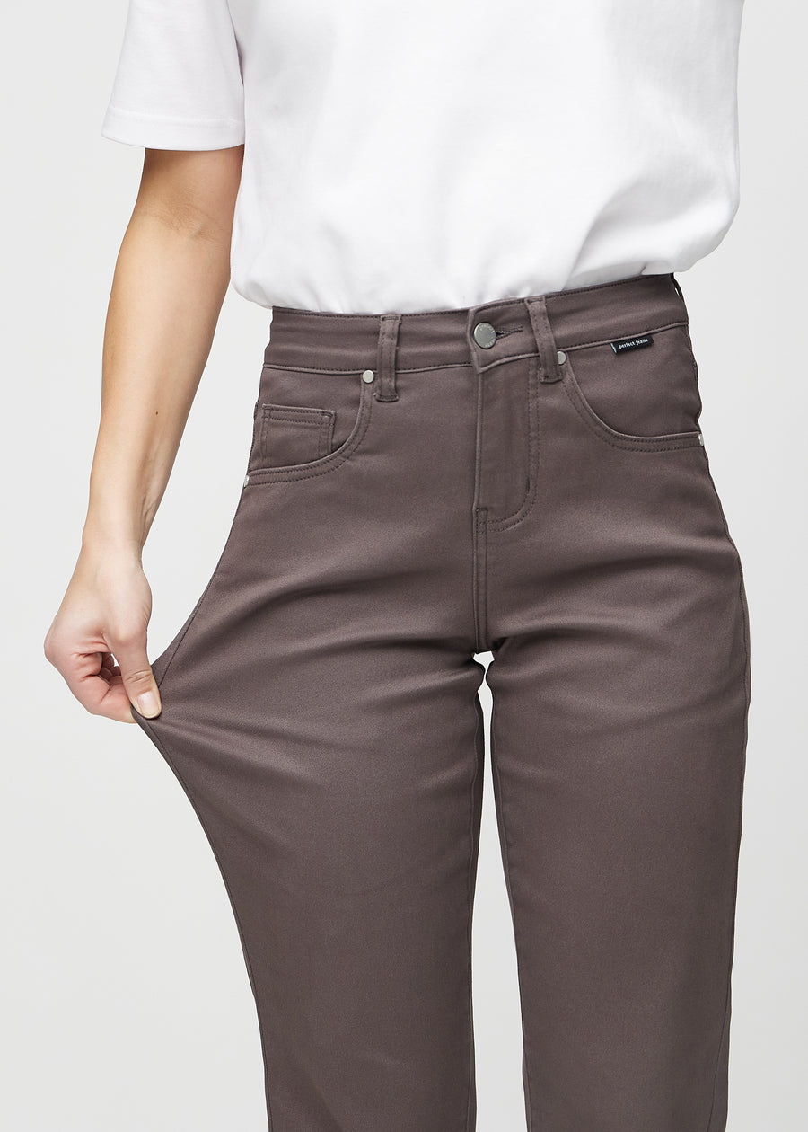 Regularjeans för kvinnor i gråbrun, färgen Thunders. En modell drar i tyget vid låret för att visa stretchen.