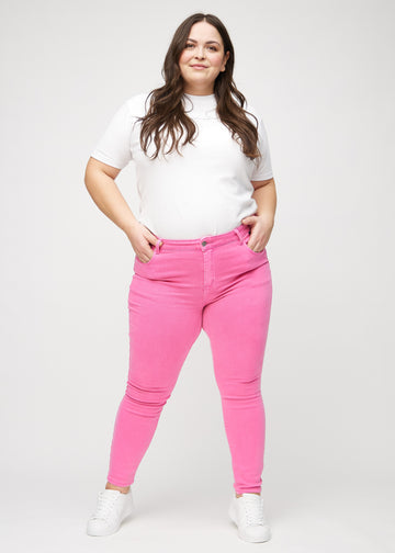 Skinnyjeans för kvinnor i ljusrosa, färgen Flamingos. Helbild av en plus size-modell i jeansen.