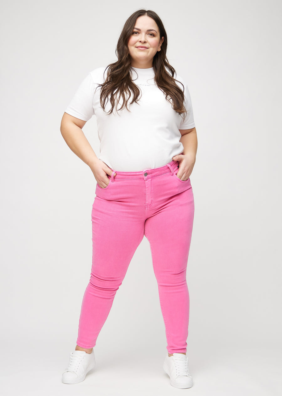 Skinnyjeans för kvinnor i ljusrosa, färgen Flamingos. Helbild av en plus size-modell i jeansen.