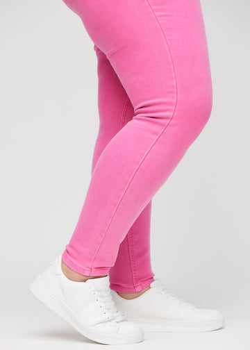 Skinnyjeans för kvinnor i ljusrosa, färgen Flamingos. Närbild vid anklarna på en plus size-modell som visar de åtsittande bensluten.