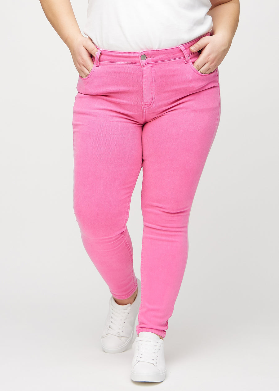 Skinnyjeans för kvinnor i ljusrosa, färgen Flamingos. Framifrån på en plus size-modell, med nära passform runt benen.