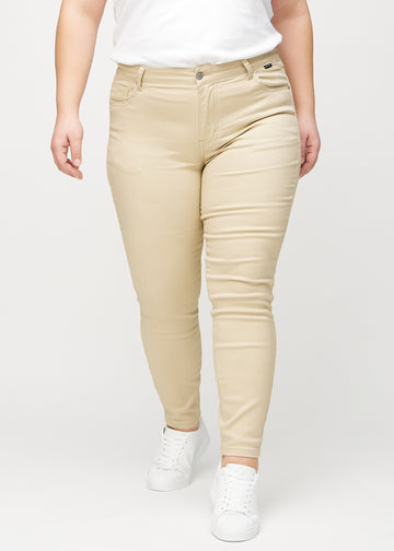 Skinnyjeans för kvinnor i beige, färgen Gazelles. Framifrån på en plus size-modell, med nära passform runt benen.