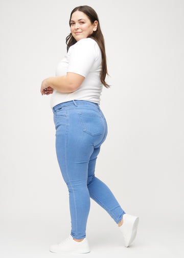 Skinnyjeans för kvinnor i blå, färgen Geraniums. Från sidan på en plus size-modell.