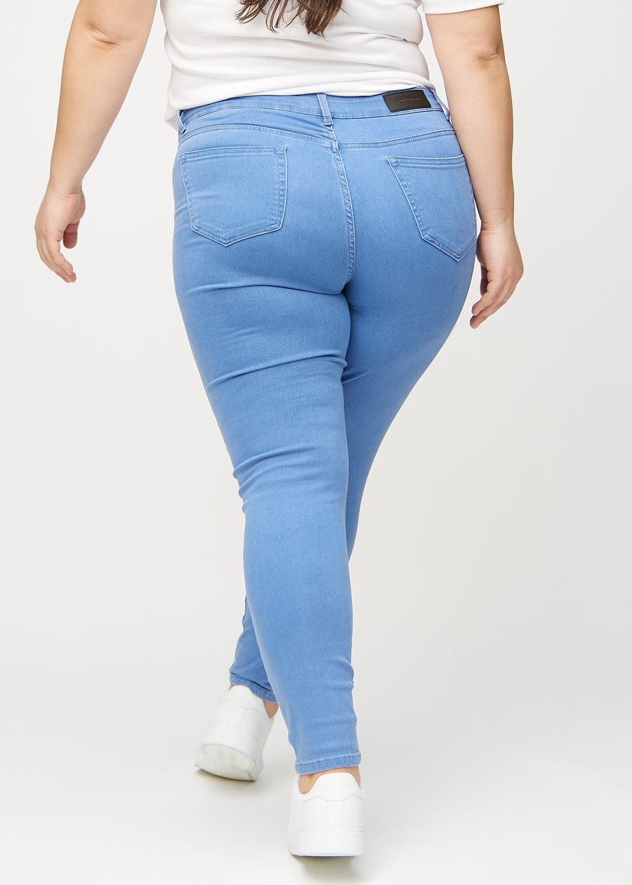 Skinnyjeans för kvinnor i blå, färgen Geraniums. Bakifrån på en plus size-modell, så att hela passformen syns.