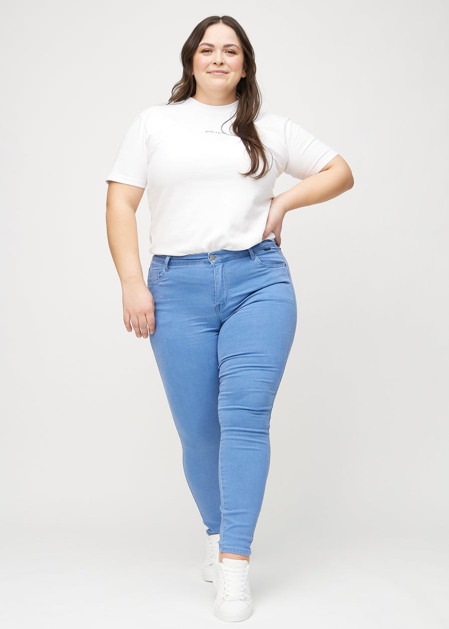 Skinnyjeans för kvinnor i blå, färgen Geraniums. Helbild av en plus size-modell som bär jeansen.