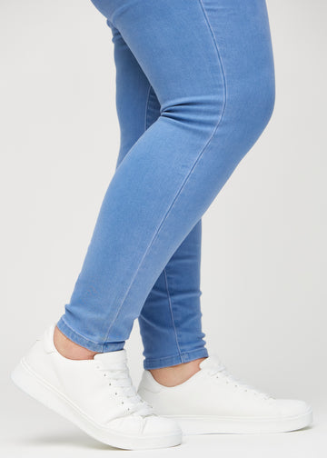 Skinnyjeans för kvinnor i blå, färgen Geraniums. Närbild vid anklarna på en plus size-modell som visar de åtsittande bensluten.