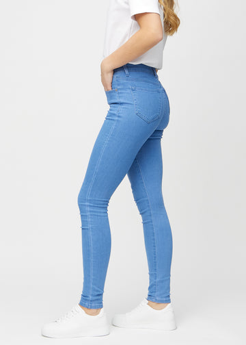 Skinnyjeans för kvinnor i blå, färgen Geraniums. Från sidan på en modell.