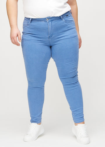Skinnyjeans för kvinnor i blå, färgen Geraniums. Framifrån på en plus size-modell, med nära passform runt benen.