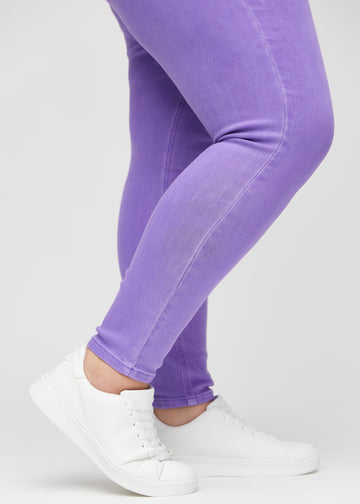 Skinnyjeans för kvinnor i lila, färgen Lavenders. Närbild vid anklarna på en plus size-modell som visar de åtsittande bensluten.