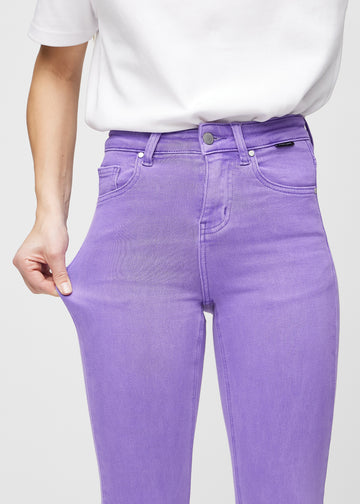 Skinnyjeans för kvinnor i lila, färgen Lavenders. En modell drar i jeanstyget vid låret för att visa stretchen.