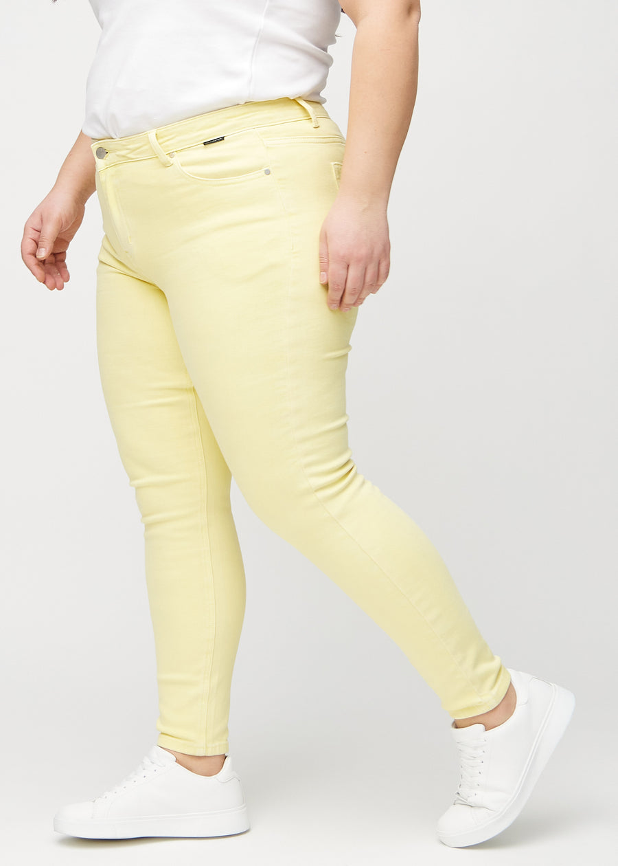 Skinnyjeans för kvinnor i ljusgul, färgen Lemonades. Från sidan på en plus size-modell.