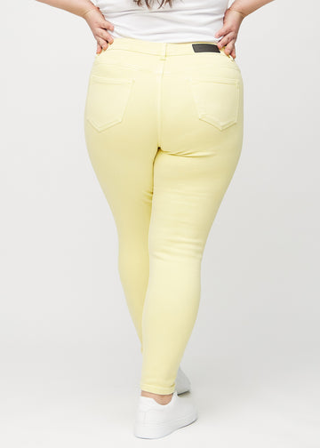 Skinnyjeans för kvinnor i ljusgul, färgen Lemonades. Bakifrån på en plus size-modell, så att hela passformen syns.
