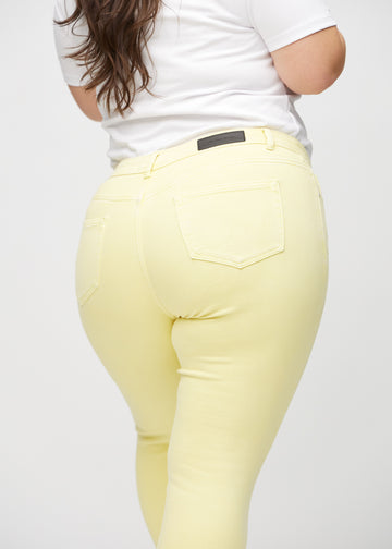 Skinnyjeans för kvinnor i ljusgul, färgen Lemonades. Närbild bakifrån på en plus size-modell som visar detaljerna.