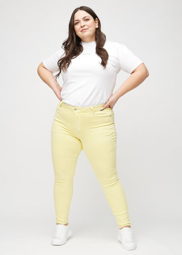 Skinnyjeans för kvinnor i ljusgul, färgen Lemonades. Helbild av en plus size-modell i jeansen.
