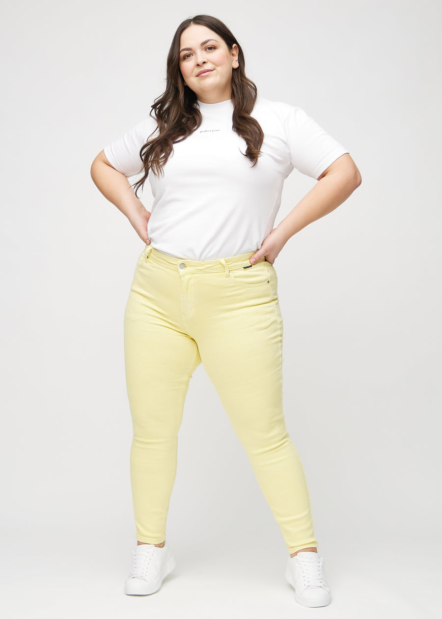 Skinnyjeans för kvinnor i ljusgul, färgen Lemonades. Helbild av en plus size-modell i jeansen.