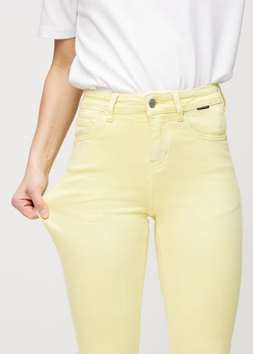 Skinnyjeans för kvinnor i ljusgul, färgen Lemonades. En modell drar i jeanstyget vid låret för att visa stretchen.
