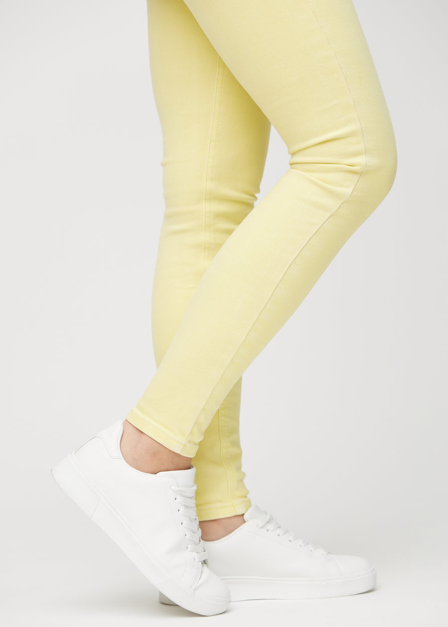 Skinnyjeans för kvinnor i ljusgul, färgen Lemonades. Närbild vid anklarna på en modell som visar de åtsittande bensluten.