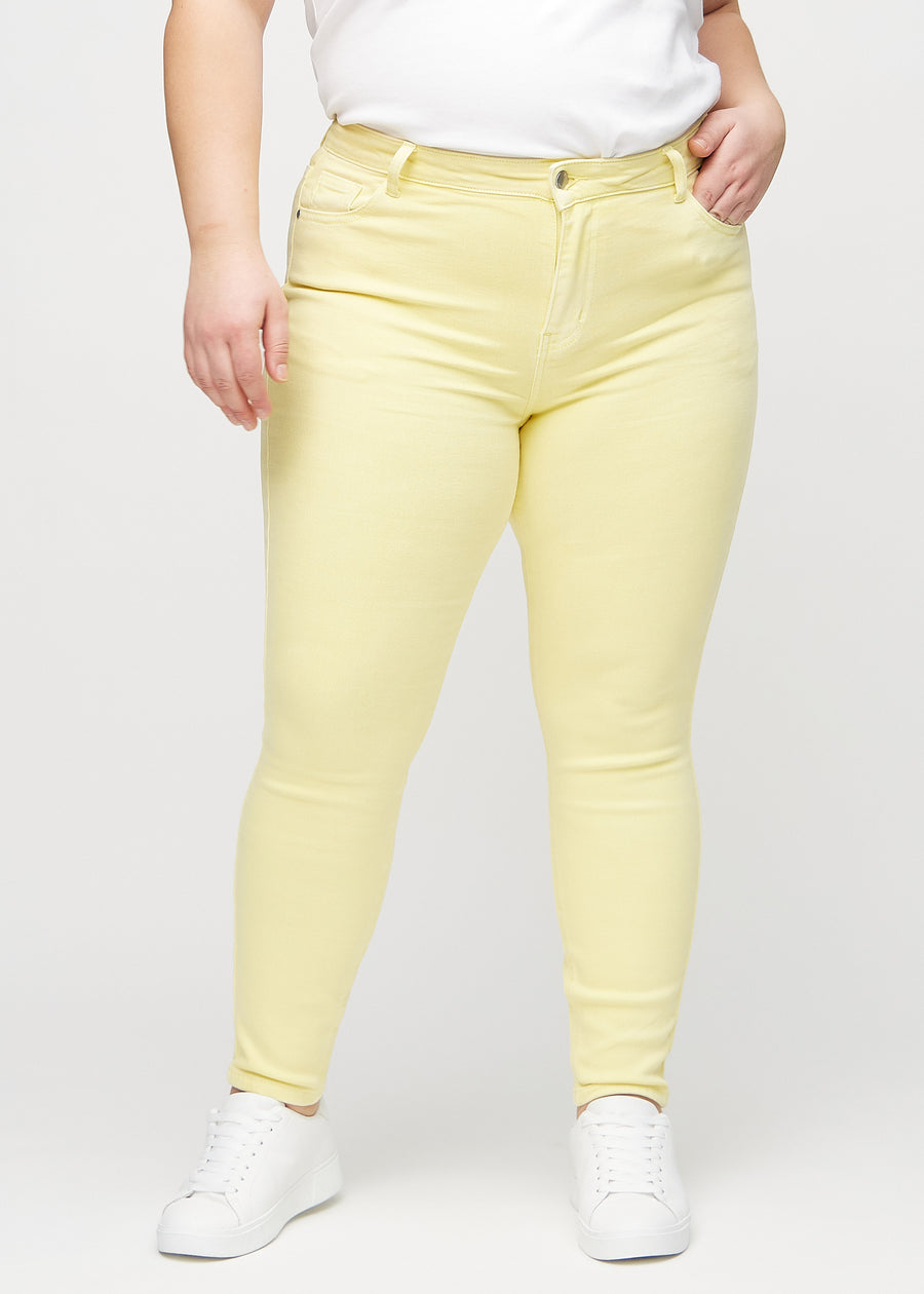 Skinnyjeans för kvinnor i ljusgul, färgen Lemonades. Framifrån på en plus size-modell, med nära passform runt benen.