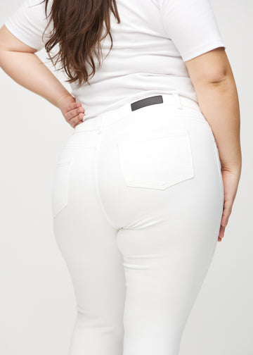 Skinnyjeans för kvinnor i vit, färgen Marguerites. Närbild bakifrån på en plus size-modell som visar detaljerna.