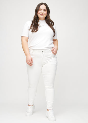 Skinnyjeans för kvinnor i vit, färgen Marguerites. Helbild av en plus size-modell i jeansen.