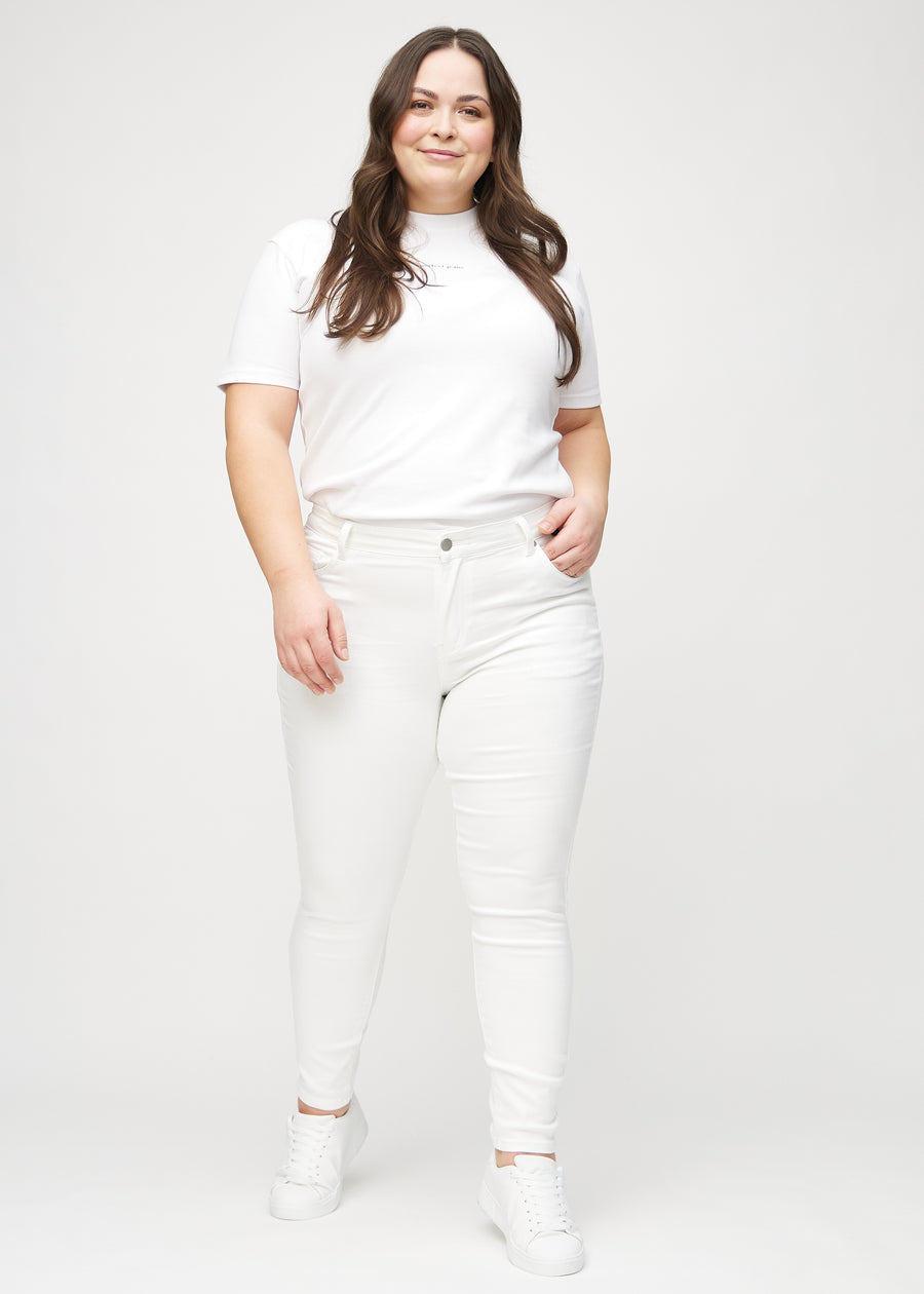 Skinnyjeans för kvinnor i vit, färgen Marguerites. Helbild av en plus size-modell i jeansen.