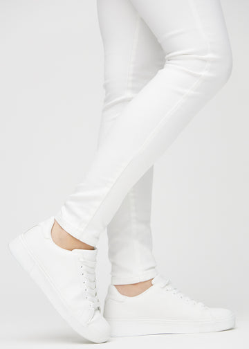 Skinnyjeans för kvinnor i vit, färgen Marguerites. Närbild vid anklarna på en modell som visar de åtsittande bensluten.