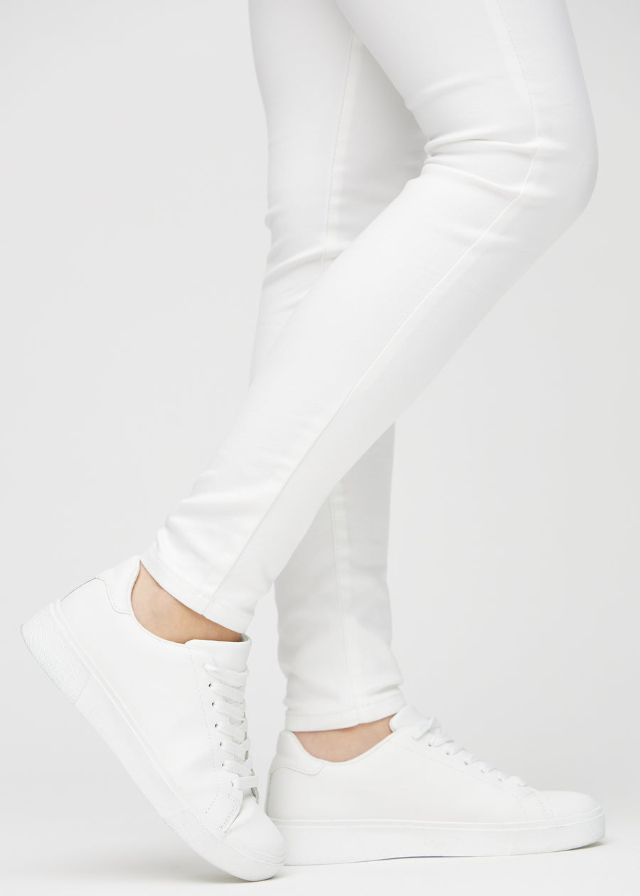 Skinnyjeans för kvinnor i vit, färgen Marguerites. Närbild vid anklarna på en modell som visar de åtsittande bensluten.