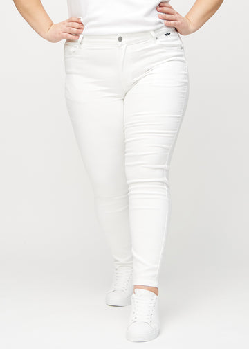 Skinnyjeans för kvinnor i vit, färgen Marguerites. Framifrån på en plus size-modell, med nära passform runt benen.